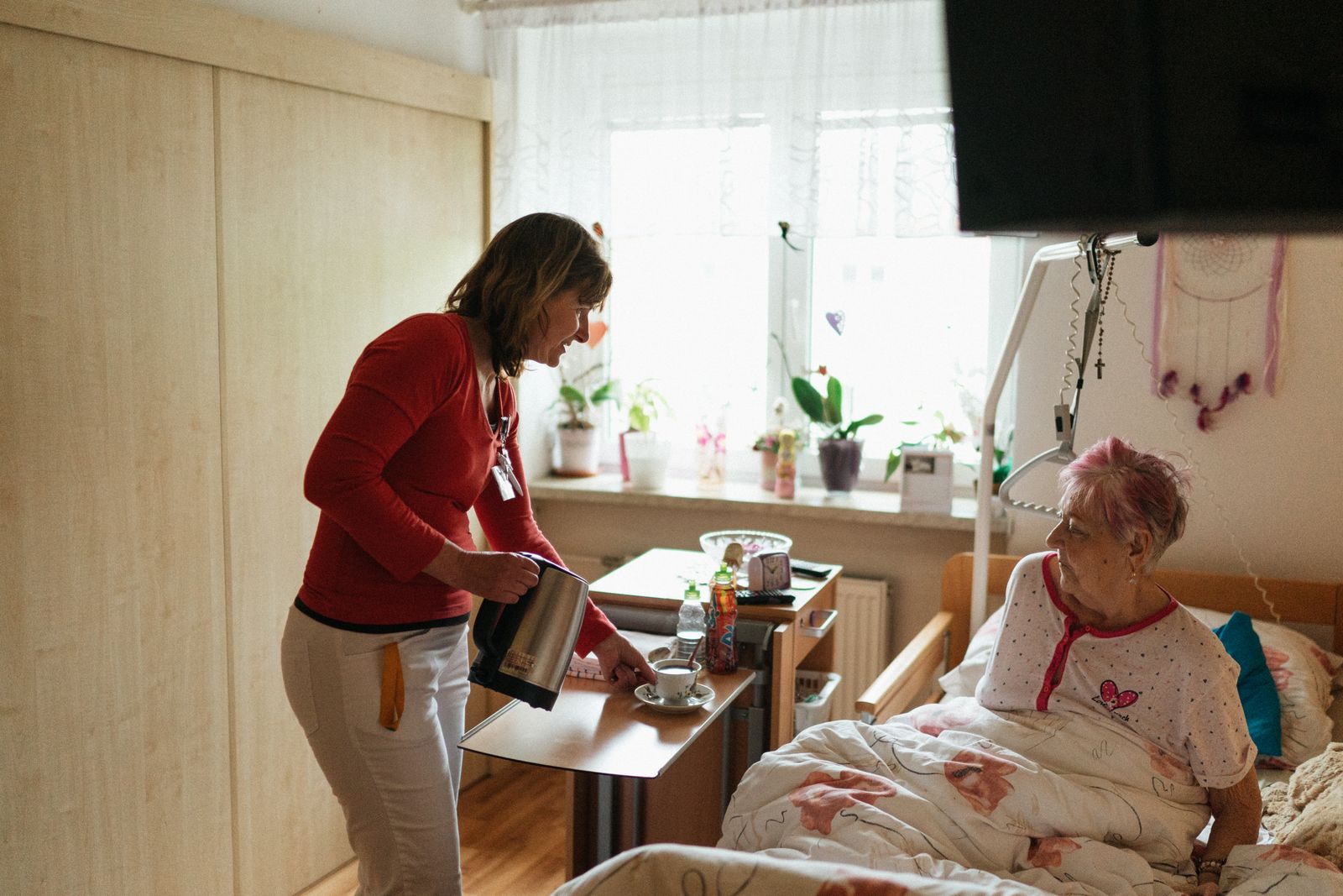 A caregiver kindly serving tea to a senior woman at home